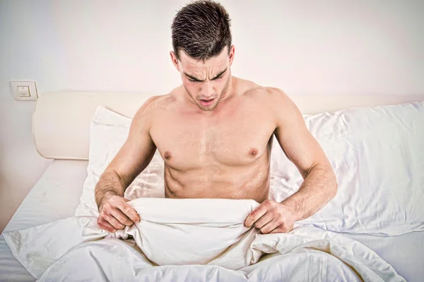 Metade nu jovem na cama olhando para baixo em sua roupa interior — Fotografia de Stock