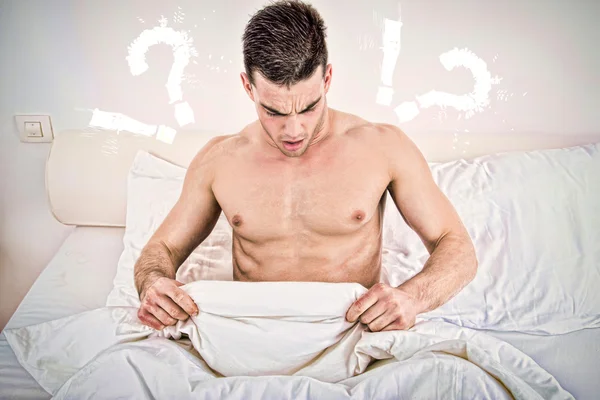 Hombre joven medio desnudo en la cama mirando hacia abajo a su ropa interior — Foto de Stock