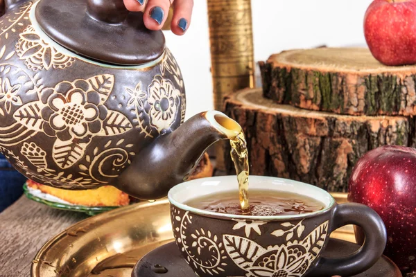 Gieten thee uit ketel op oude houten tafel met fruit — Stockfoto