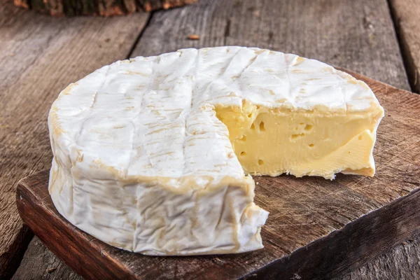 Στρογγυλό τυρί σε ρουστίκ ξύλινη σανίδα — Φωτογραφία Αρχείου