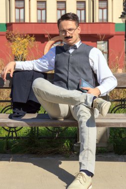 Bir kitapla bankta oturan kendine güvenen zarif adam