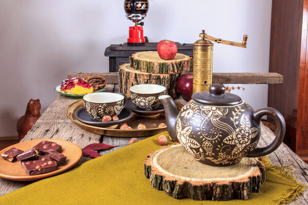 Cups of tea on old wooden table, with apples and nuts