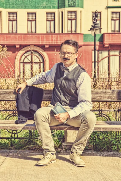 Elegant man sitting on the bench relaxing with a book — Stock Photo, Image