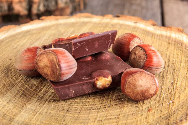 Кусочки шоколада с орехами на пне — стоковое фото