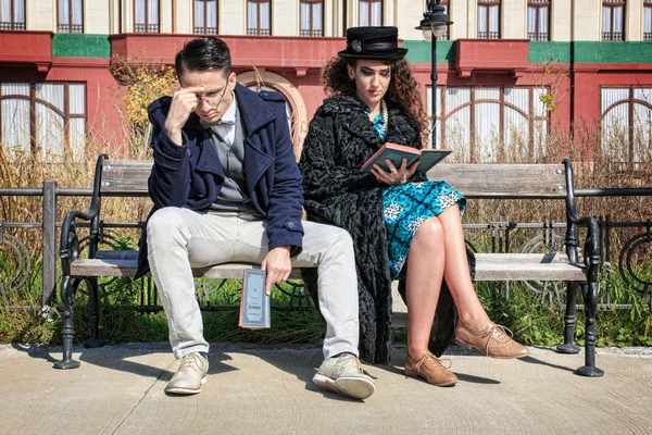 Ungt retro par i gräl sitter på bänken läser bok — Stockfoto