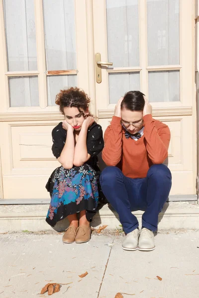 Agité homme et femme accroupi devant la maison à l'escalier — Photo