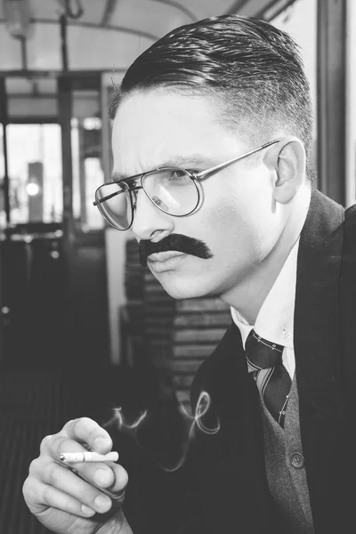 Black  and white photo of man with glasses in a suit sitting in — Stock Photo, Image