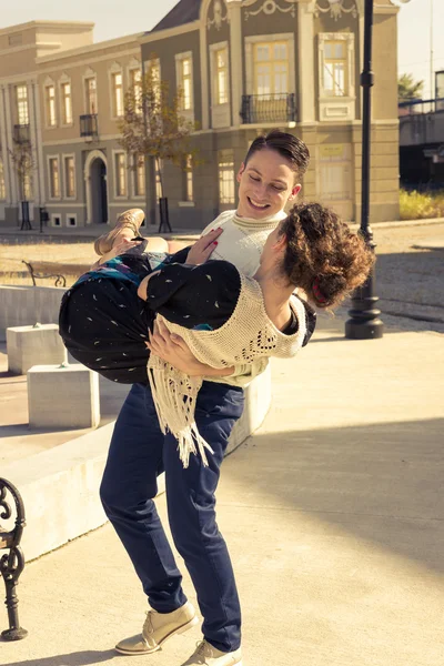 Bonito sorrindo homem levantou feliz mulher em suas mãos no meio do — Fotografia de Stock