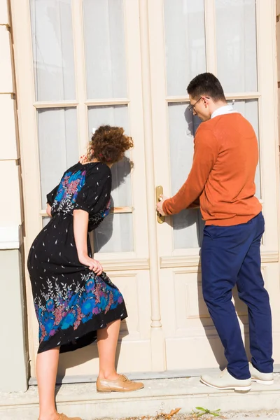 Hombre con gafas en el suéter naranja con la mujer tratando de ope —  Fotos de Stock