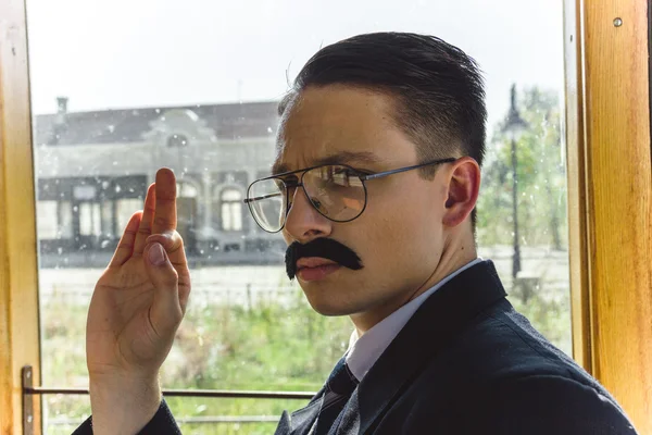 Old photo of man in suit with a mustache and glasses on the trai — Stock Photo, Image