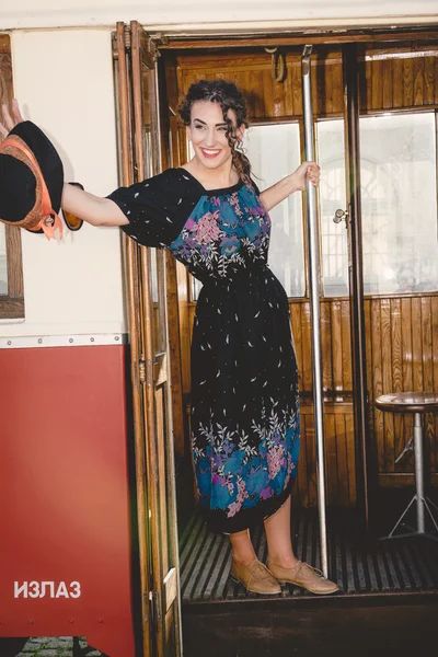 Retro image of smiling young woman waving in the wooden wagon tr — Stock Photo, Image