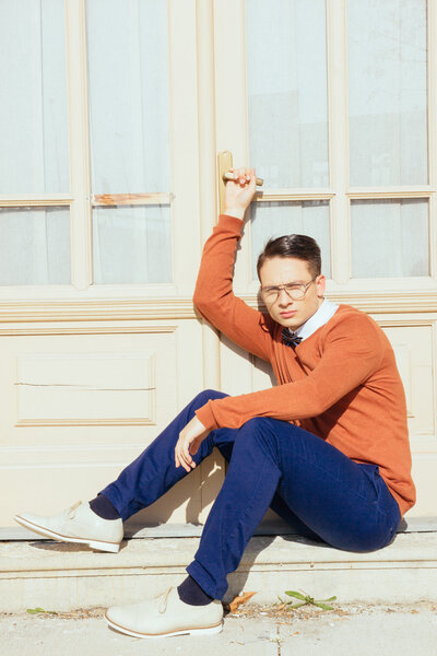 serious handsome man with glasses and sweater sitting on steps i