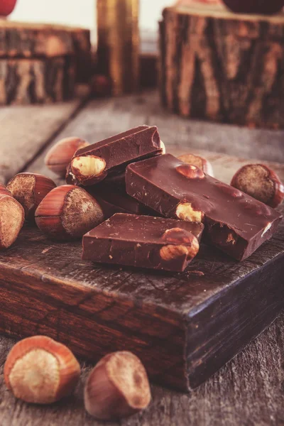 Kostka czekolady z orzechy laskowe lub orzechy wokół drewniane kołowy — Zdjęcie stockowe