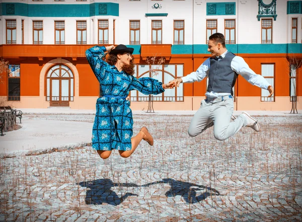 Счастливая пара в любви прыгает в воздухе высоко в середине улицы — стоковое фото