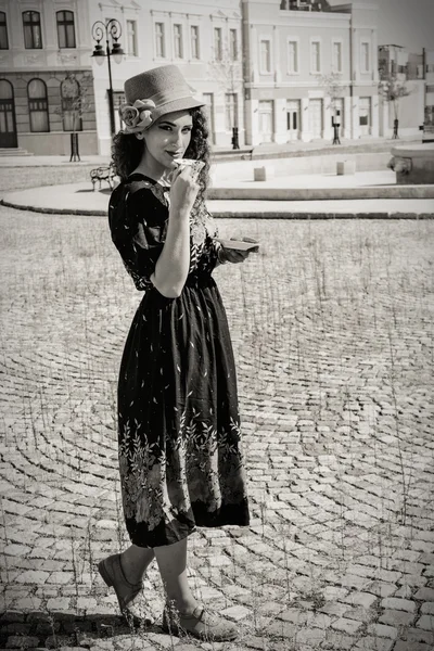 Hübsche Frau in Retro-Kleid und Hut, die Heißgetränk oder Bier trinkt — Stockfoto