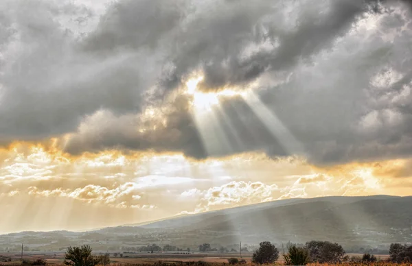 Pôr do sol dourado através das nuvens sobre o céu dramático na paisagem conc — Fotografia de Stock