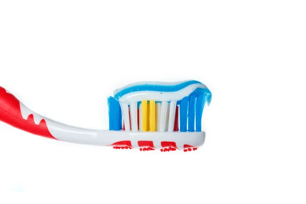 Brosse à dents rouge avec deux couleurs bleu dentifrice sur la surface de la lumière — Photo