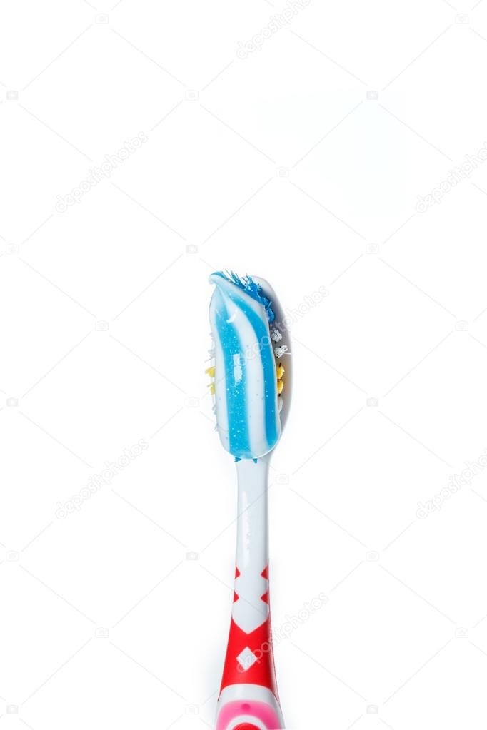 toothbrush with blue two color toothpaste on light surface
