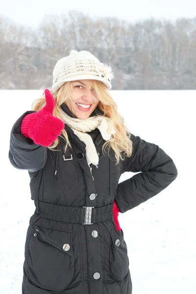 Woman in snow looking up at camera with thumb up outside — Stock Photo, Image