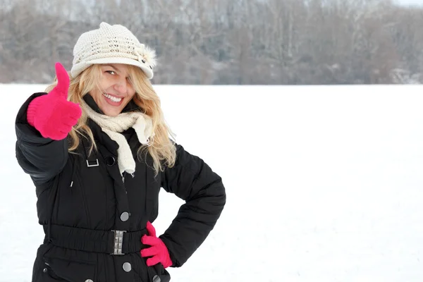 Happy woman in snow looking up at camera with thumb up — Stock Photo, Image