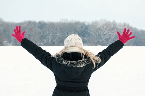 Woman in snow showing her back and facing forest with hands rais — Stock Photo, Image