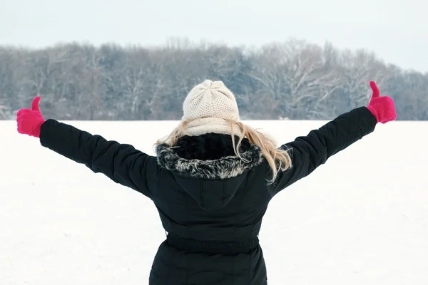 Woman in snow showing her back and facing forest with thumbs up — Stock Photo, Image