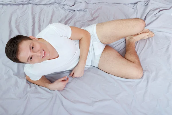 Young man in white t-shirt and underwear sitting or sitting on a — Stock Photo, Image