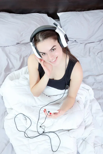 Chica en pijama con reproductor de mp3 o móvil y auriculares disfrute — Foto de Stock