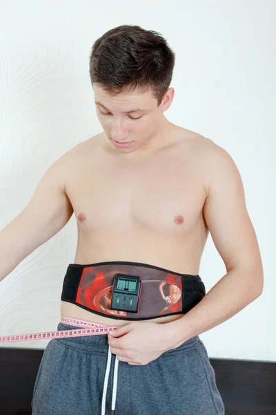 Smiling Half-naked handsome young man with an electrical device Royaltyfria Stockfoton