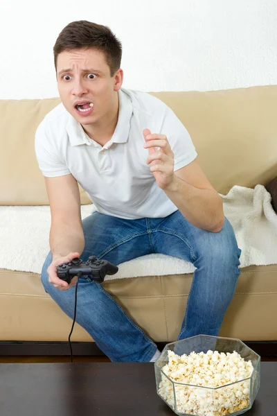 Guy eating popcorn with joystick for game console — Stock Photo, Image