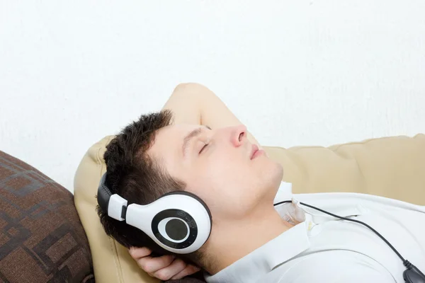 Young man daydreaming listening to music over headset — Stock Photo, Image