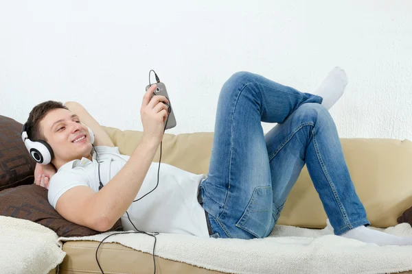 Joven sonriendo disfrutando de la música con auriculares y celular —  Fotos de Stock