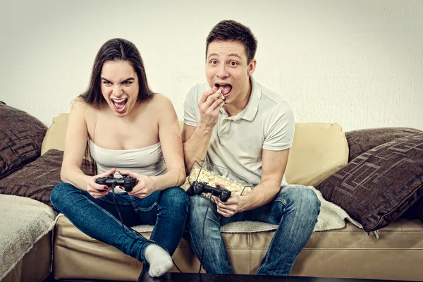 Couple amoureux sur canapé assis et jouer à des jeux vidéo dans la vie Images De Stock Libres De Droits