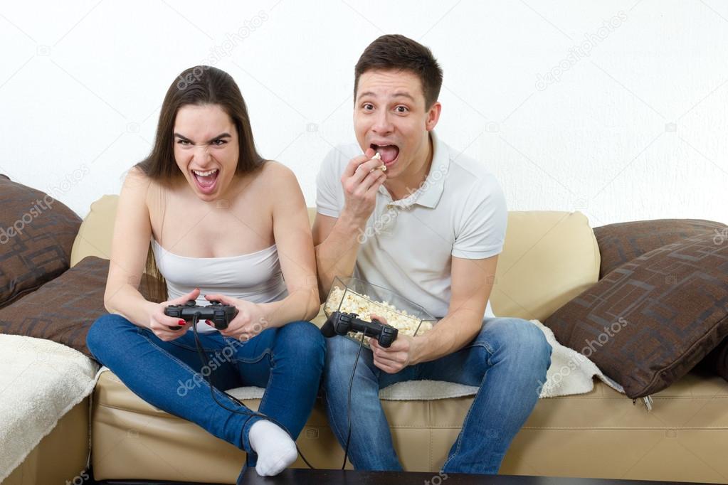 couple in love on sofa sitting and playing video games in living