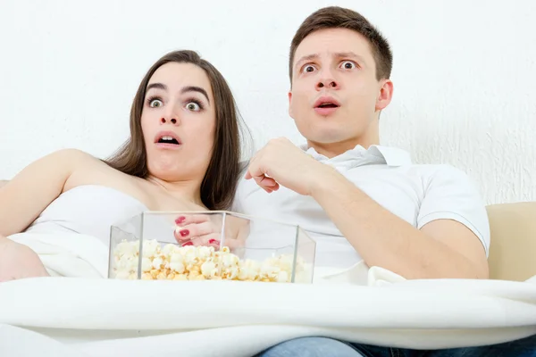 Couple sitting on the couch in living room at home covered with — Stock Photo, Image