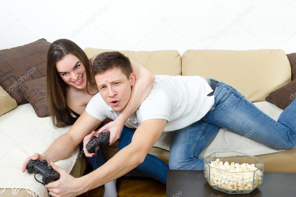  couple sitting in living room and play video games on console o