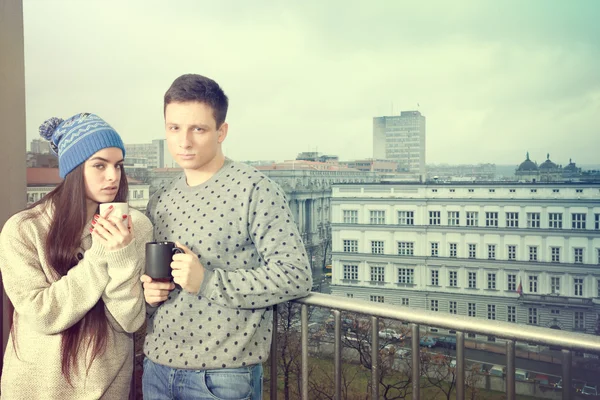 Pareja feliz en el amor abrazo cerca barandilla con tazas de té o co —  Fotos de Stock