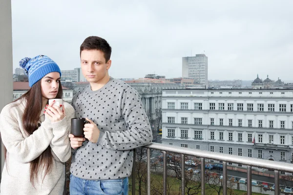 Pareja feliz en el amor abrazo cerca barandilla con tazas de té o co — Foto de Stock