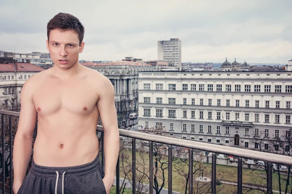 Shirtles joven guapo en pantalones de chándal de pie en la terraza —  Fotos de Stock