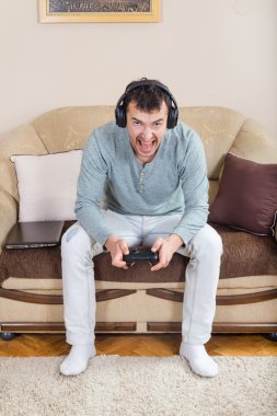 Kablosuz Bluetooth joystick ile video oyun oynarken genç adam