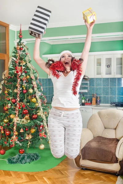 Aufgeregte junge Frau springt vor Freude mit Geschenken in den Händen — Stockfoto
