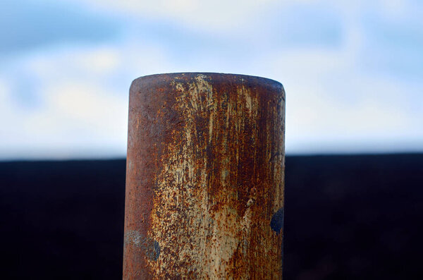 Rusty iron pipe in the field close up