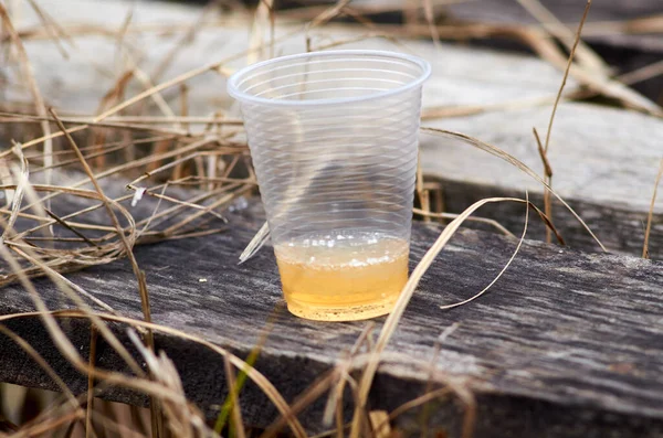 Plastic cup with beer on wood close up