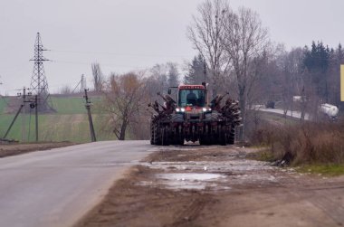 Disk harrows ile bir traktör yol boyunca sürücüler