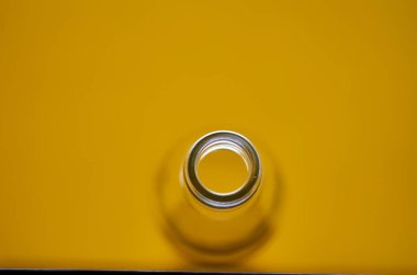 Boş cam şişenin fotoğrafı. Sarı arkaplan.