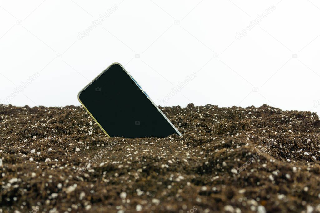 View of a phone stuck in the ground on a white background