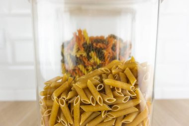 Temiz plastik bir kavanozun içinde bütün tahıllı makarna yakın plan.