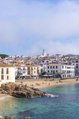 GIRONA, SPAIN - 31 Mart 2021: COSTA BRAVA 'daki CALELLA DE PALAFRUGELL kasabasında Akdeniz kıyısındaki kumsalda ve kayalıklarda yaşayan insanlar