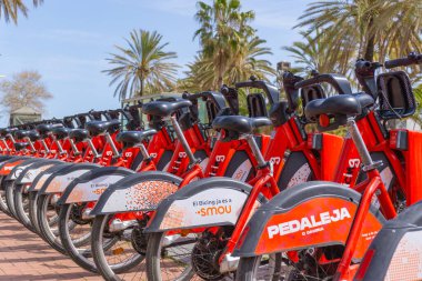 BARCELONA, İspanya - 1 Nisan 2021: BARCELONA şehrinin sokaklarında bir bisiklet parkında kırmızı kiralanmış bisiklet sıraları