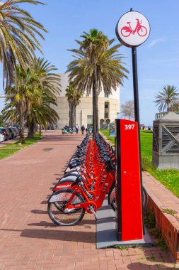 BARCELONA, İspanya - 1 Nisan 2021: BARCELONA şehrinin sokaklarında bir bisiklet parkında kırmızı kiralanmış bisiklet sıraları